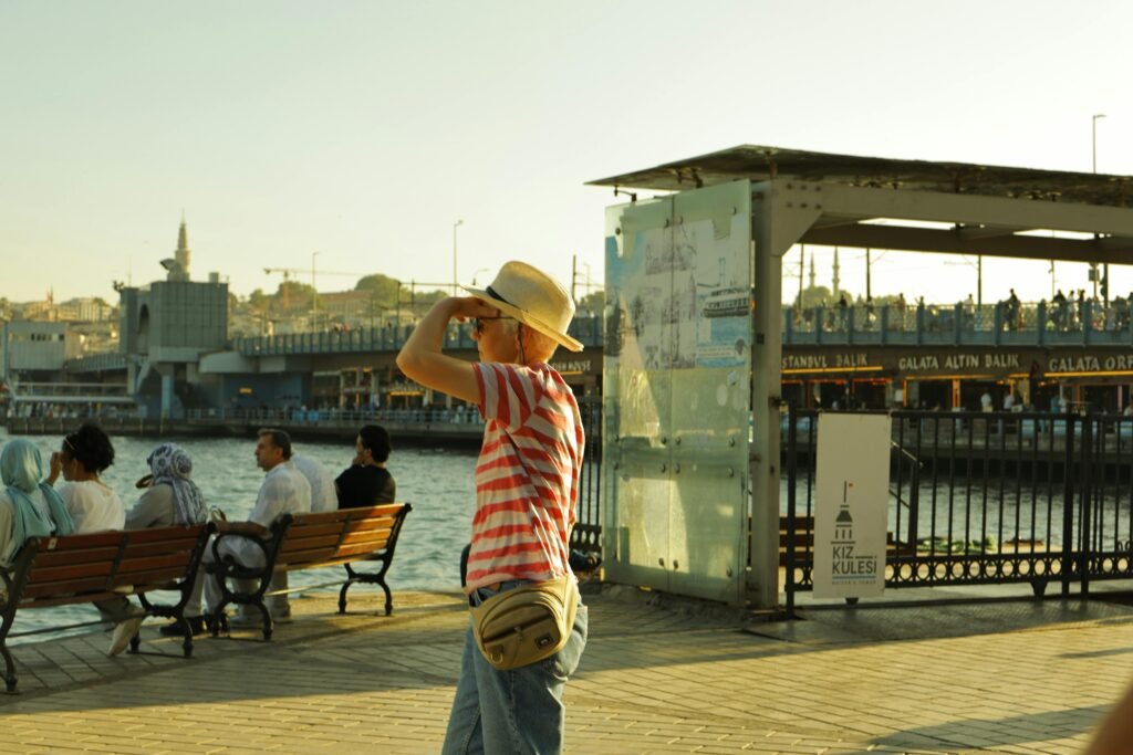 Tourist in hat enjoys sunny day by Istanbul waterfront near Galata Bridge.