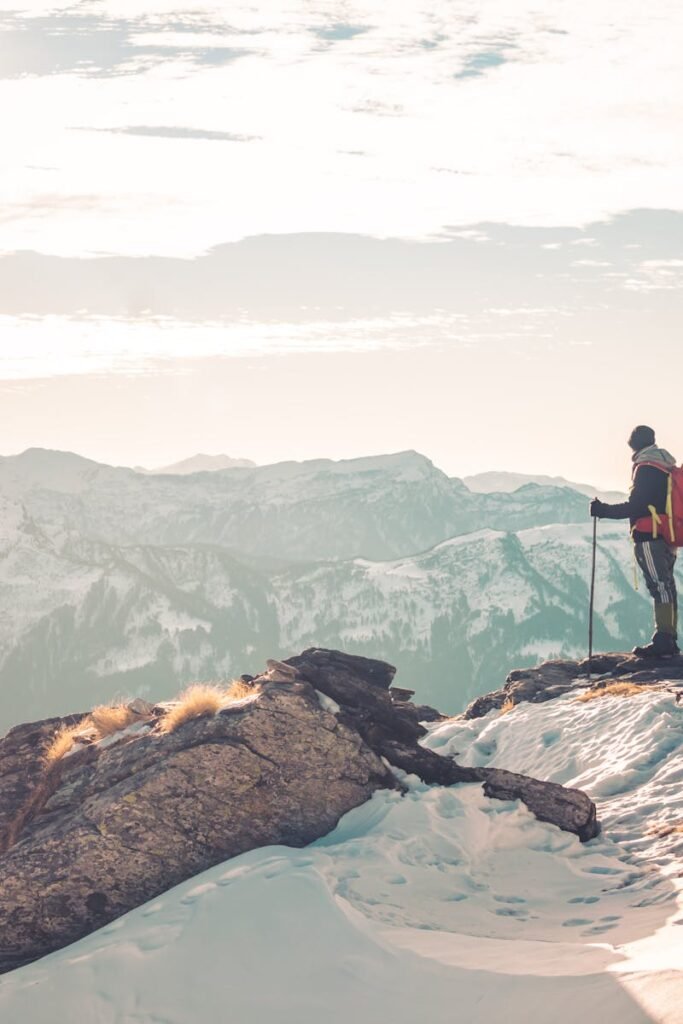 A backpacker standing atop snowy mountains, exploring the serene Himalayan landscape.