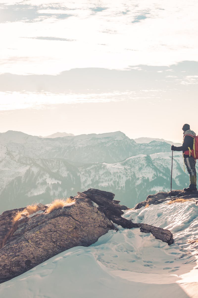 A backpacker standing atop snowy mountains, exploring the serene Himalayan landscape.